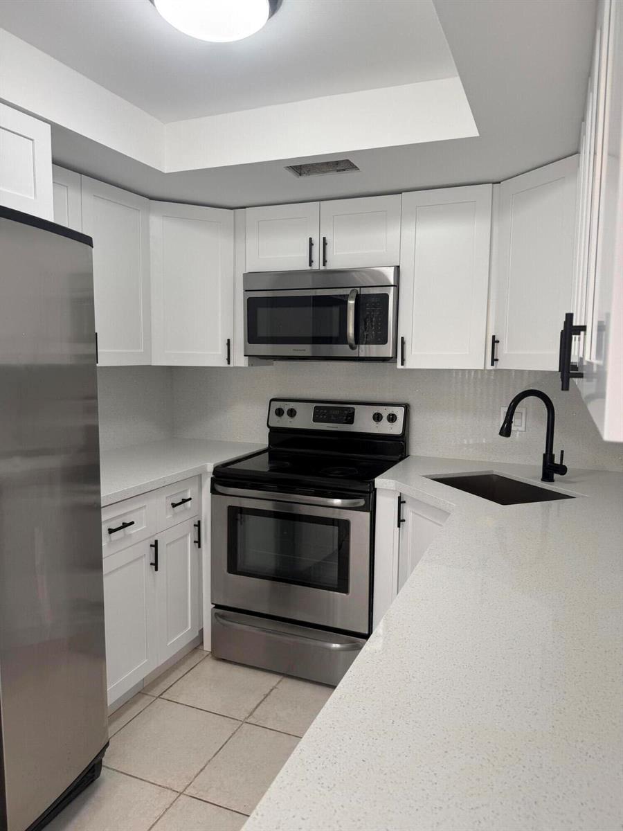 A kitchen with white cabinets, stainless steel appliances, and light-colored quartz countertops — 217 Foxtail Drive # H, FL 33415, FL