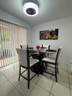 A dining area features a glass-topped table with four white chairs under a modern light — 217 Foxtail Drive # H, FL 33415, FL
