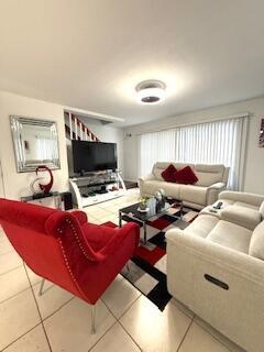A living room features a red armchair, a beige sofa, and a television on a stand — 217 Foxtail Drive # H, FL 33415, FL