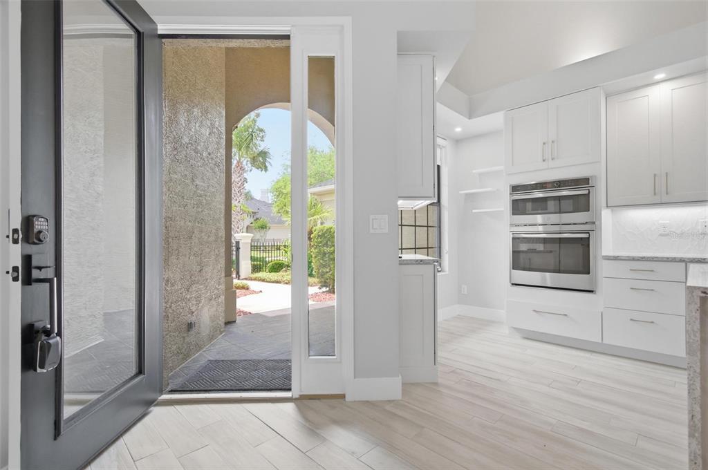 A view from an open front door looking into a kitchen with white cabinetry — 19 RIVER LANDING DRIVE, PALM COAST, FL
