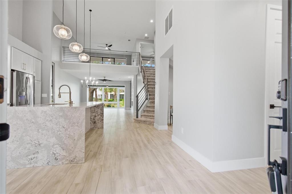 A modern kitchen with a stone island overlooks a living area with stairs and loft — 19 RIVER LANDING DRIVE, PALM COAST, FL