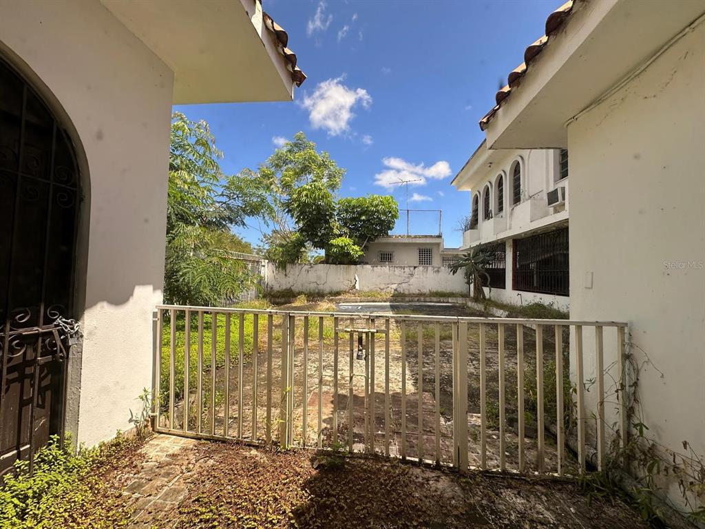 A gated outdoor courtyard sits between two white buildings under a blue sky — 5 Calle 519 QB6 URBANIZACIÓN COUNTRY CLUB, CAROLINA, PR