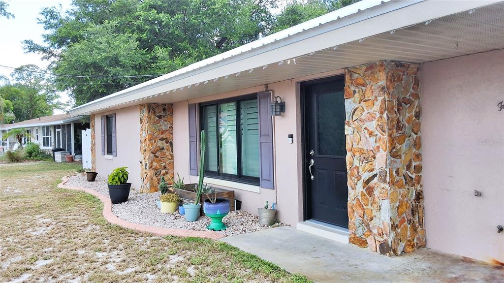 A single-story house exterior features pink stucco walls, stone accents, and a black front door — 40 SE CHINICA DRIVE, SUMMERFIELD, FL