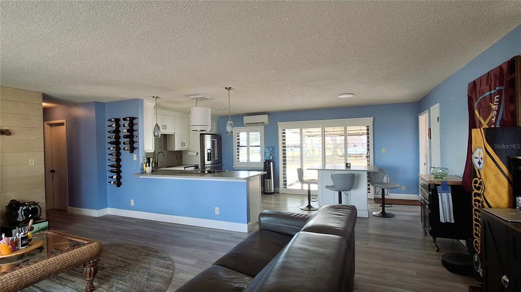 A living room and kitchen area with light blue walls, wood-look flooring, and a breakfast bar — 40 SE CHINICA DRIVE, SUMMERFIELD, FL
