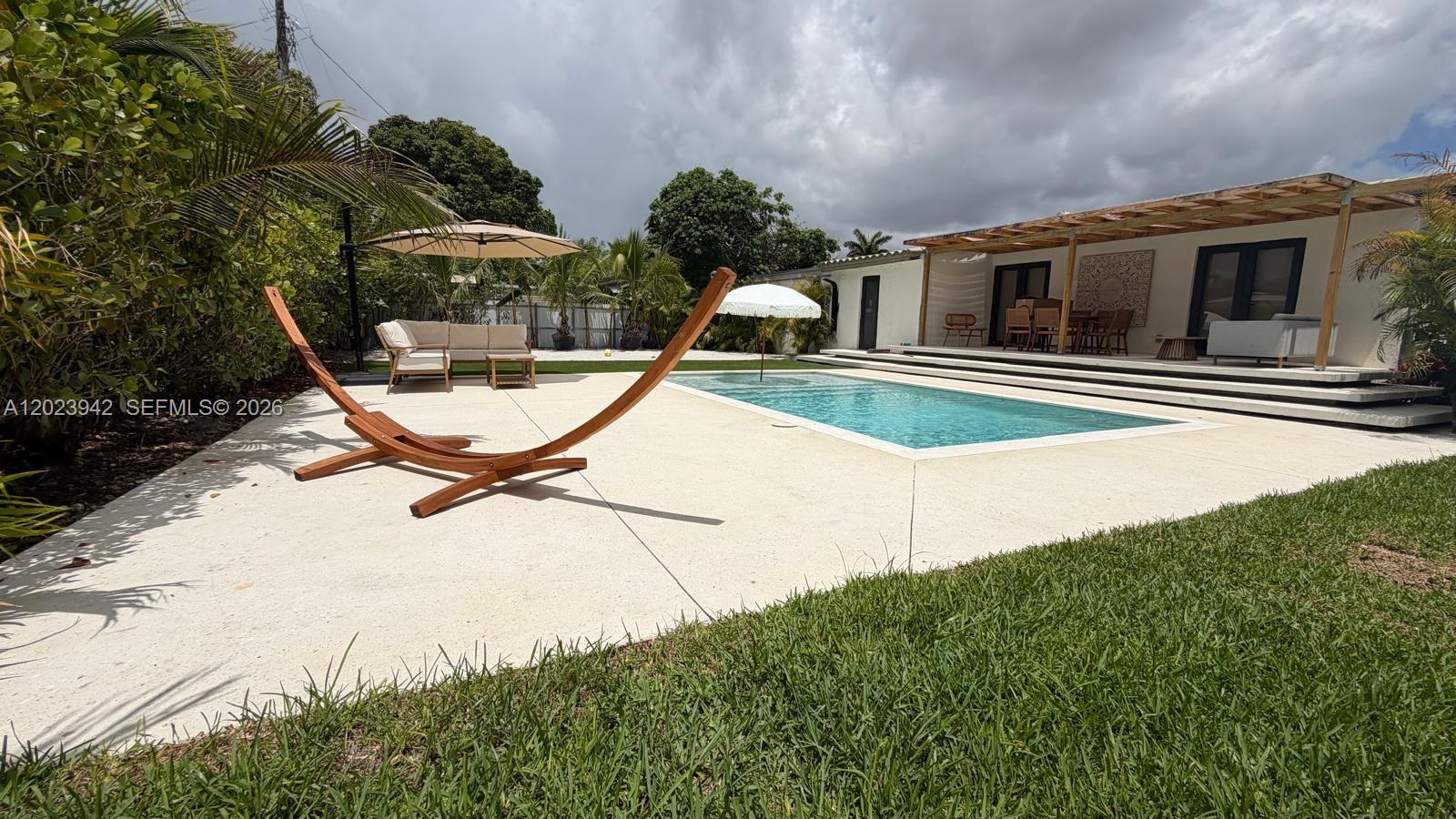 A backyard features a swimming pool, a wooden hammock stand, and a covered patio area — 3800 NW 12th St, Miami FL 33126, MIAMI, FL