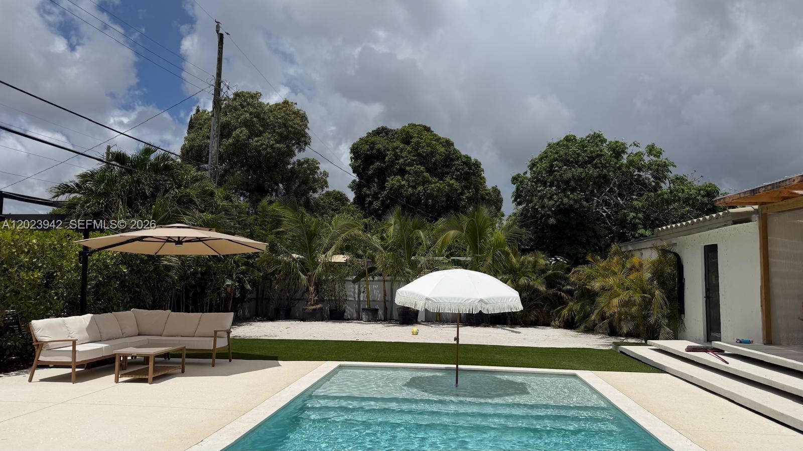 A backyard features a swimming pool, a white patio umbrella, and outdoor seating on artificial turf — 3800 NW 12th St, Miami FL 33126, MIAMI, FL