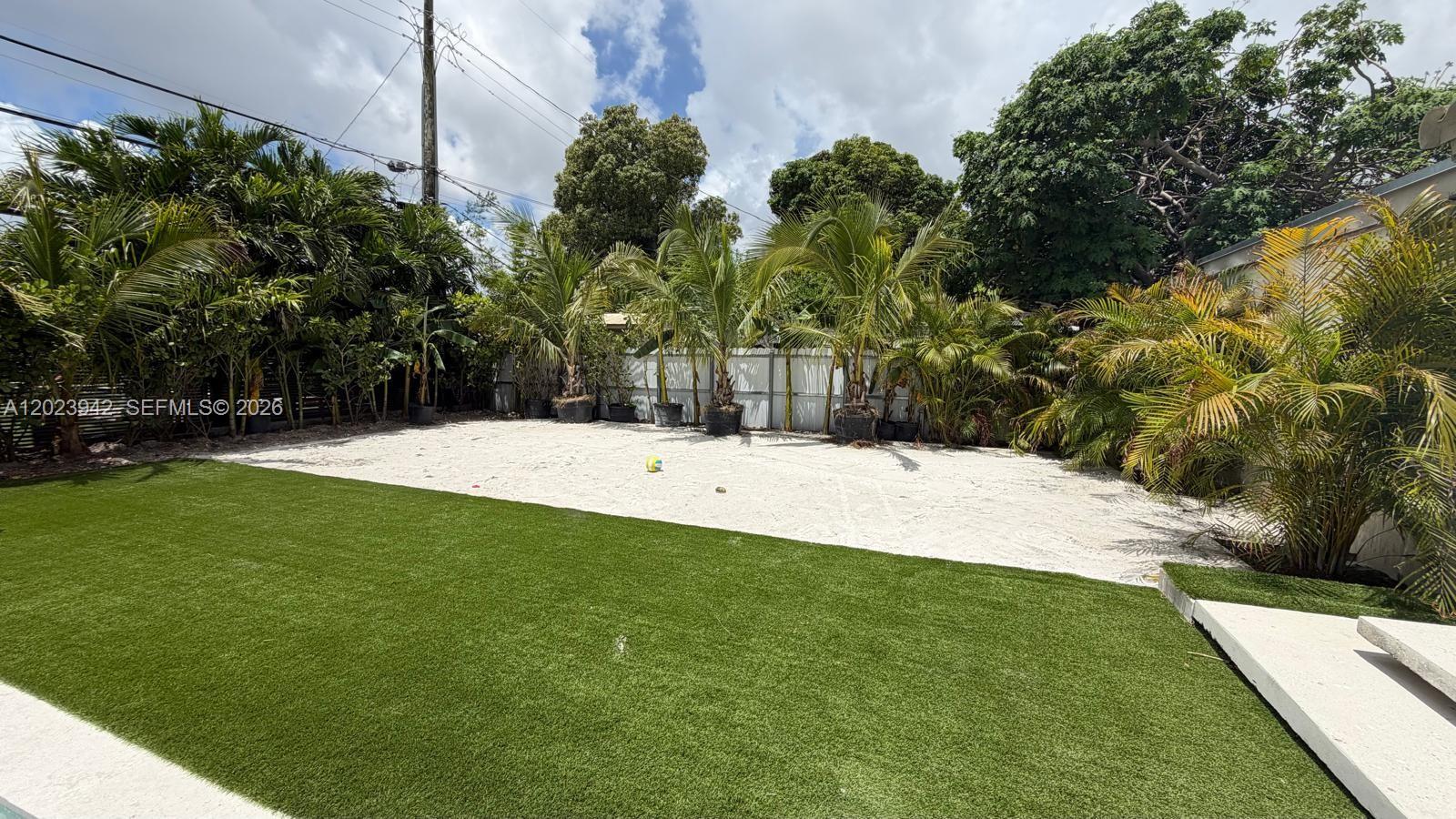A backyard features a patch of artificial turf leading to a sandy area with palms — 3800 NW 12th St, Miami FL 33126, MIAMI, FL
