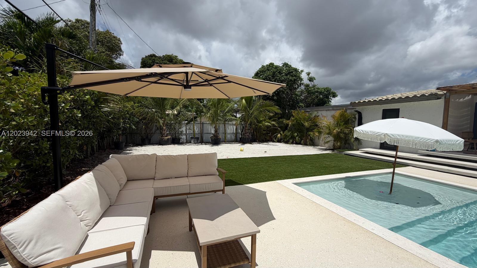 A backyard features a swimming pool, a sectional sofa under an umbrella, and artificial turf — 3800 NW 12th St, Miami FL 33126, MIAMI, FL