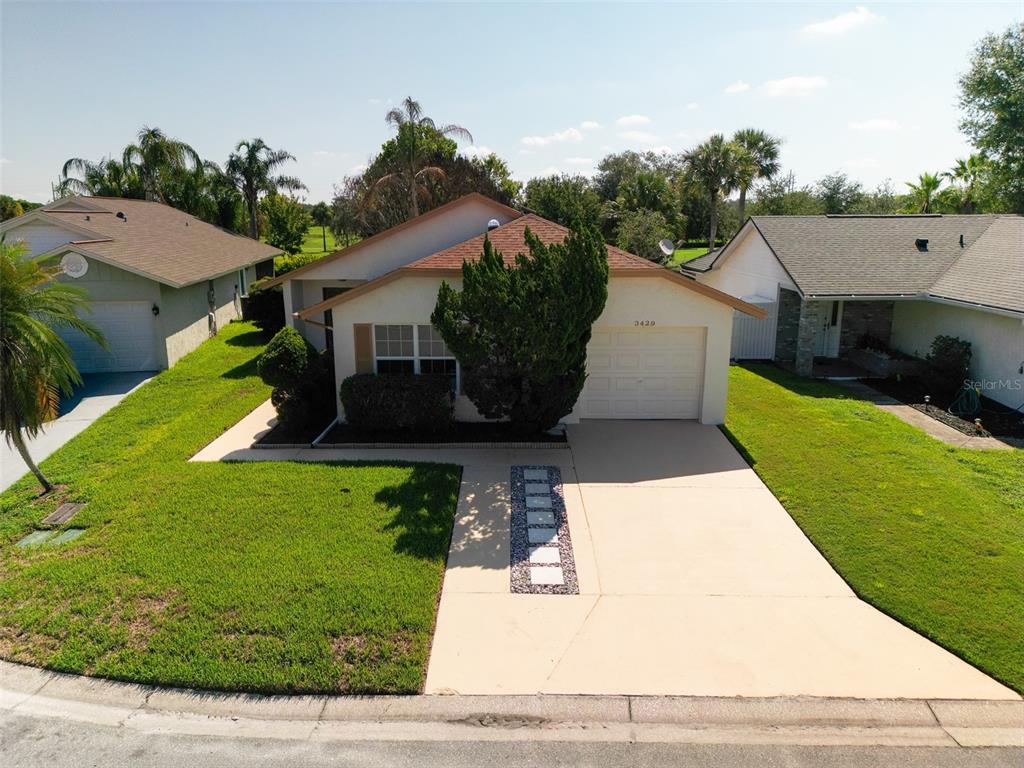 An exterior view of a single-story house with a tan stucco facade and a driveway — 3429 PINEBROOK COURT, ORLANDO, FL