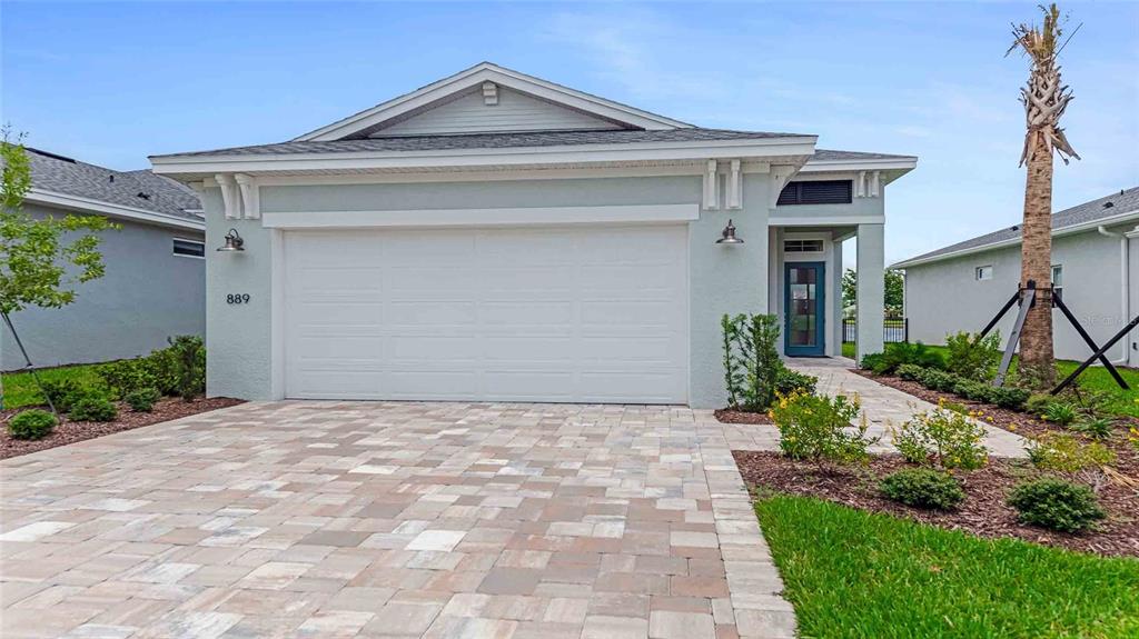 A light blue single-story house features a two-car garage and a paved driveway — 889 MEGANO BOULEVARD, DELAND, FL
