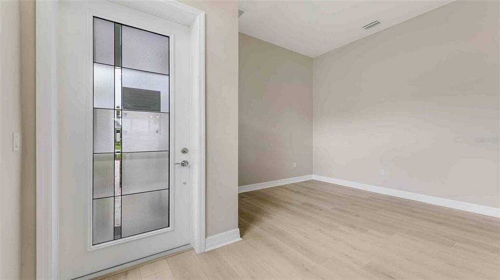 A bright entryway features a white front door with decorative glass panels and light-colored flooring — 889 MEGANO BOULEVARD, DELAND, FL