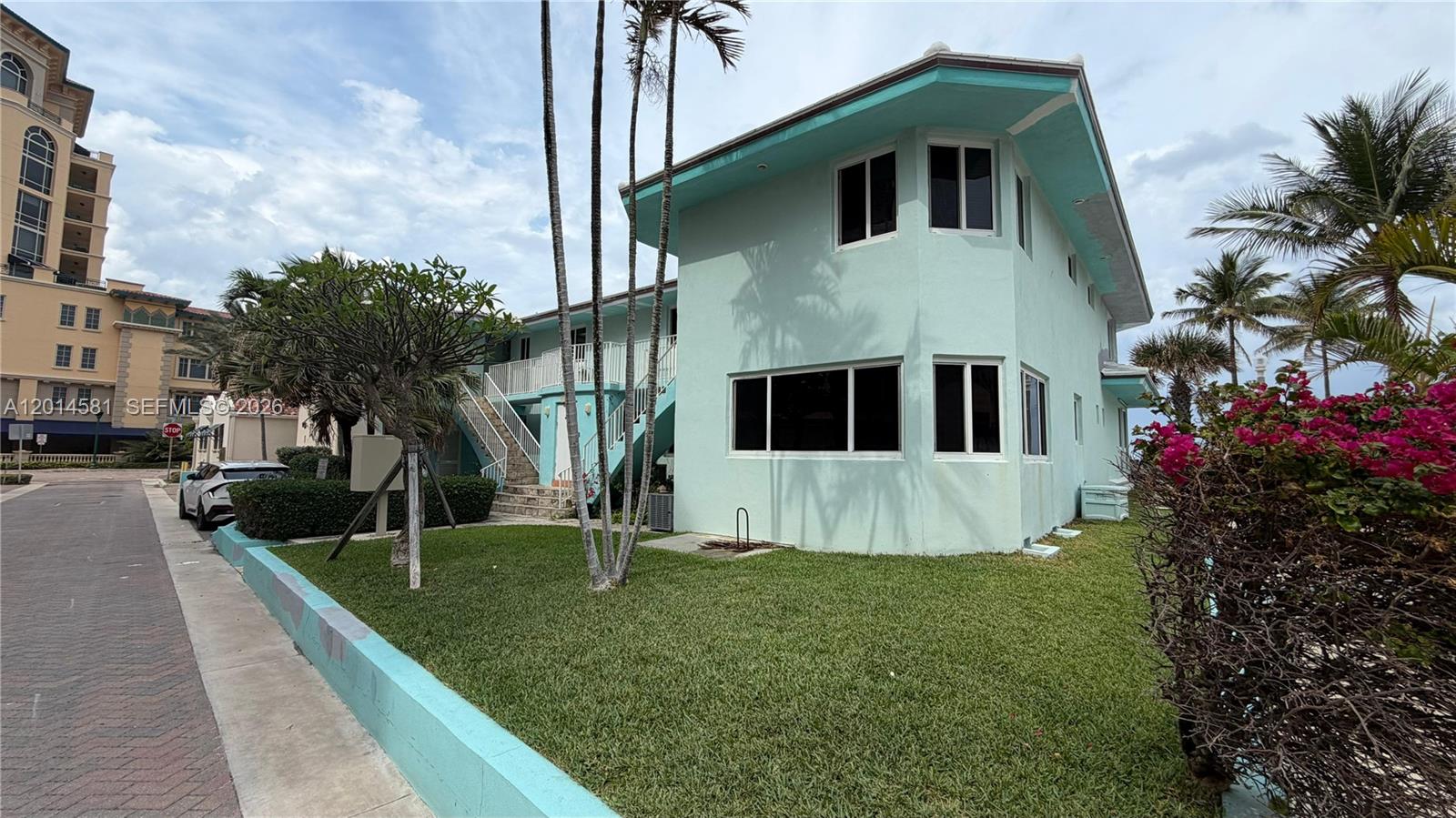 A two-story light green building with exterior stairs and palm trees on a grassy lot — 3400 N Surf Rd # 1, Hollywood FL 33019, HOLLYWOOD, FL