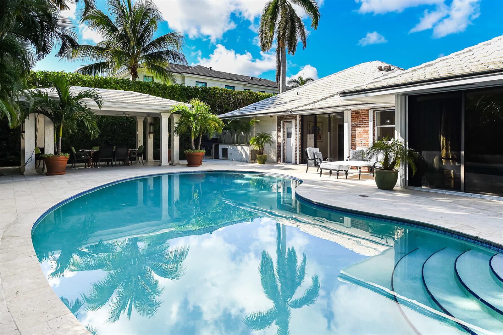 A backyard swimming pool with a covered patio and palm trees under a blue sky — 202 Coral Lane, Palm Beach FL 33480, PALM BEACH, FL