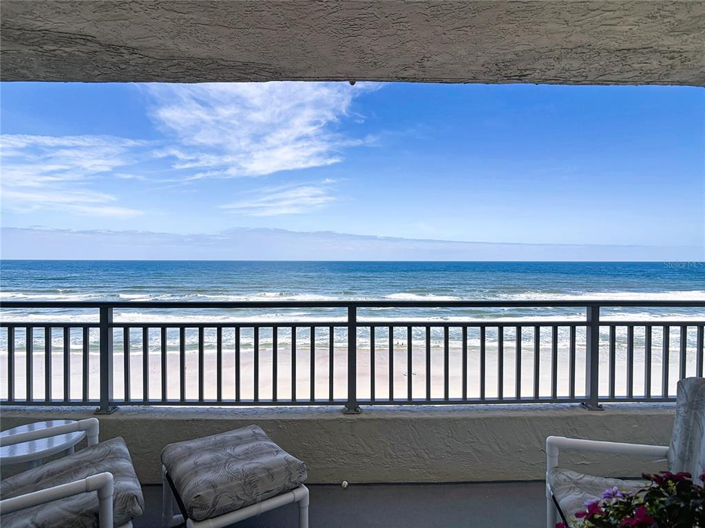 A balcony with patio furniture overlooks the ocean and sandy beach — 5207 S ATLANTIC AVENUE UNIT 822, NEW SMYRNA BEACH, FL