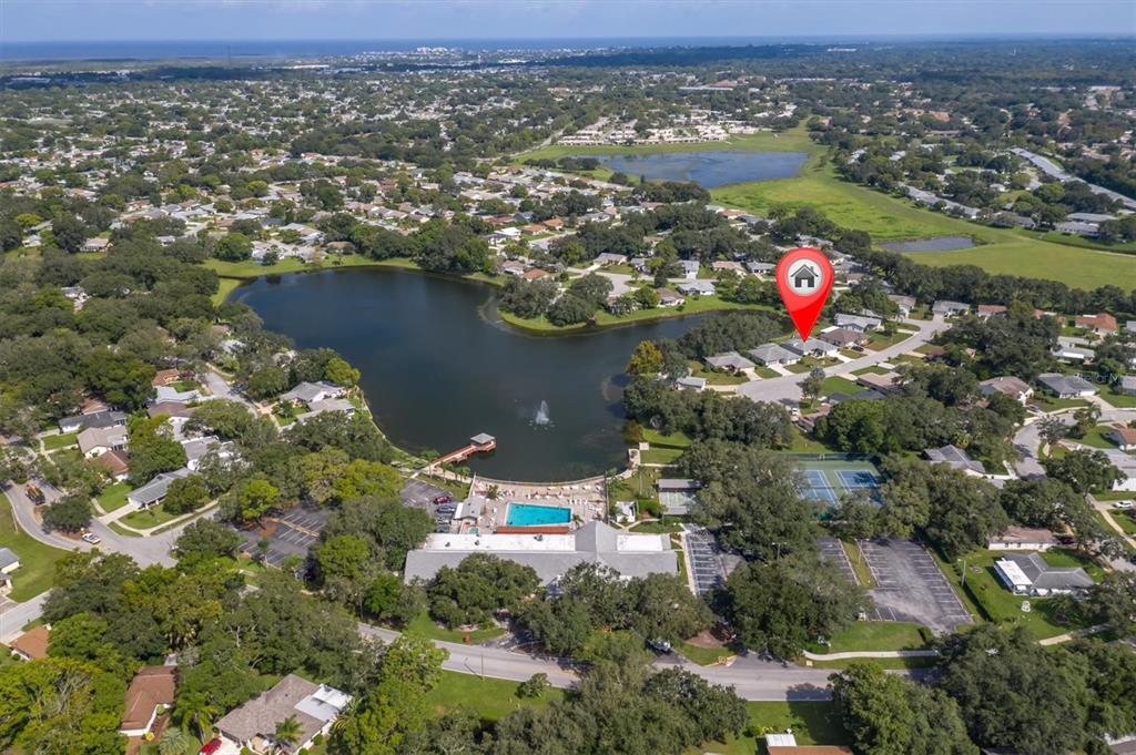 Aerial view of a residential neighborhood featuring a lake, community pool, and tennis courts — 10721 FOOTPRINT LANE, PORT RICHEY, FL
