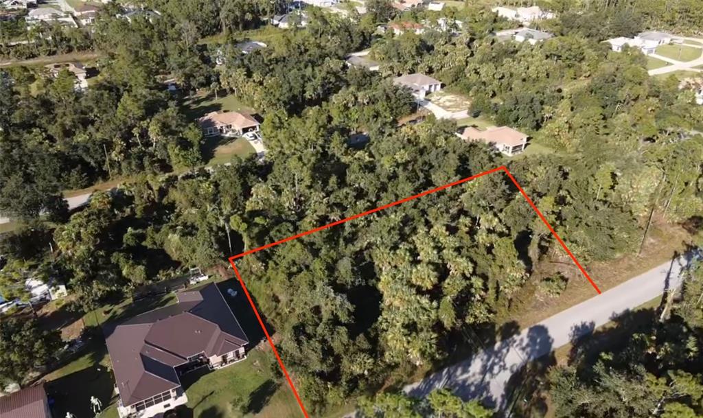 An aerial view shows a vacant, wooded residential lot outlined in red next to houses — Lot 5 & 6 COUNTESS AVENUE, NORTH PORT, FL