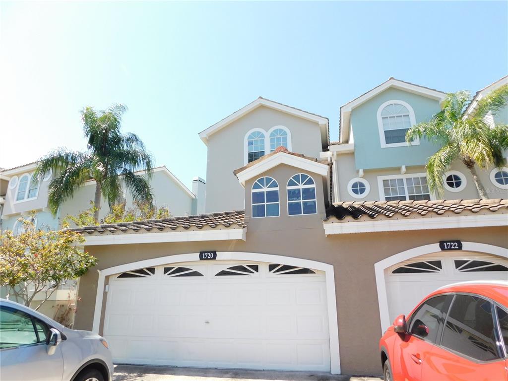 The exterior of a multi-story residential building features two garage doors and arched windows — 1720 ARABIAN LANE, PALM HARBOR, FL