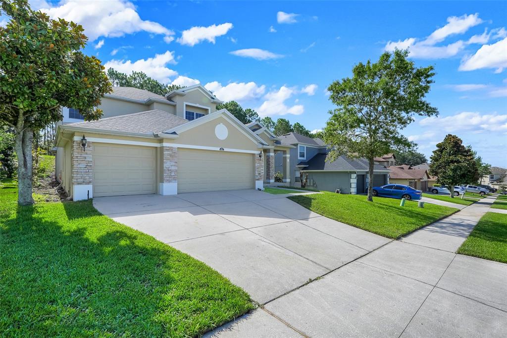 A tan two-story house with a three-car garage and a concrete driveway — 1832 NATURE COVE LANE, CLERMONT, FL