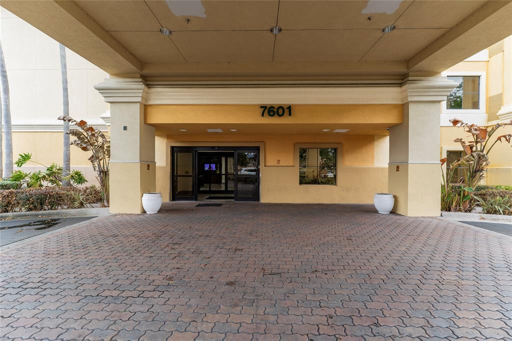 The exterior entrance of a building features a covered driveway with brick pavers — 7601 CANADA AVENUE UNIT 408, ORLANDO, FL