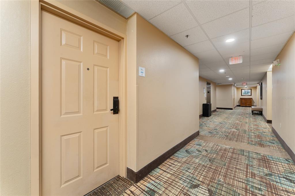A beige door with a keyless lock opens into a carpeted hotel hallway — 7601 CANADA AVENUE UNIT 408, ORLANDO, FL