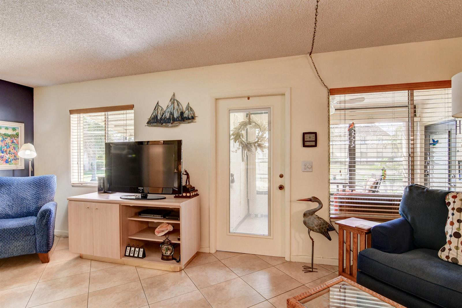 A living room features tile floors, a television on a cabinet, and two blue armchairs — 334 Pine Ridge Circle # 1, FL 33463, FL