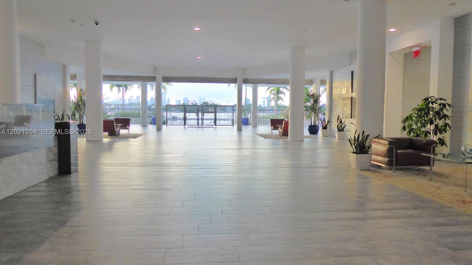A spacious, modern lobby features light tile flooring, white columns, and a view of water — 800 West Ave # 509, Miami Beach FL 33139, MIAMI BEACH, FL