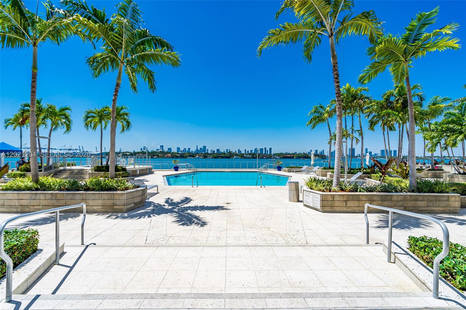 A swimming pool overlooks a bay with a city skyline in the background — 800 West Ave # 509, Miami Beach FL 33139, MIAMI BEACH, FL