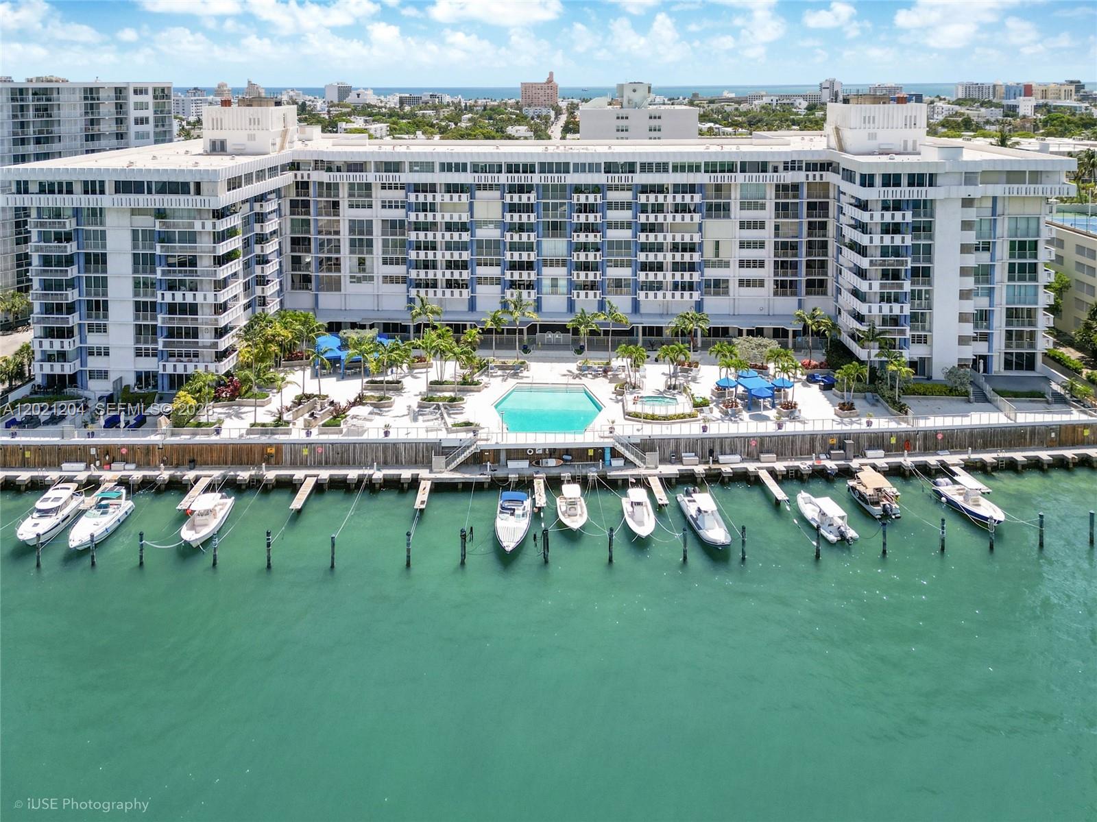 An aerial view shows a large waterfront apartment building with a pool and boat slips — 800 West Ave # 509, Miami Beach FL 33139, MIAMI BEACH, FL