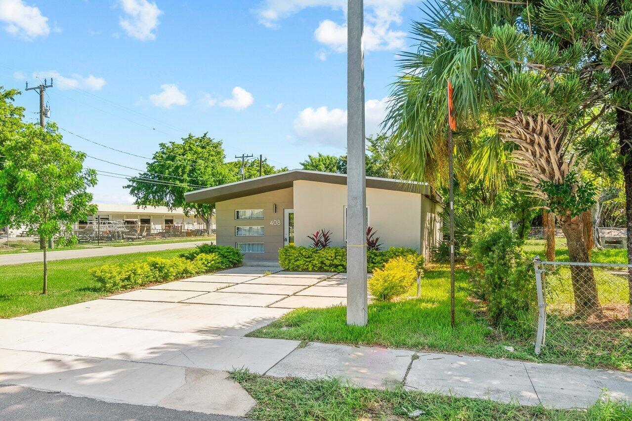 A single-story house with a flat roof and a concrete driveway sits on a lawn — 408 SW 4th Street, Delray Beach FL 33444, DELRAY BEACH, FL