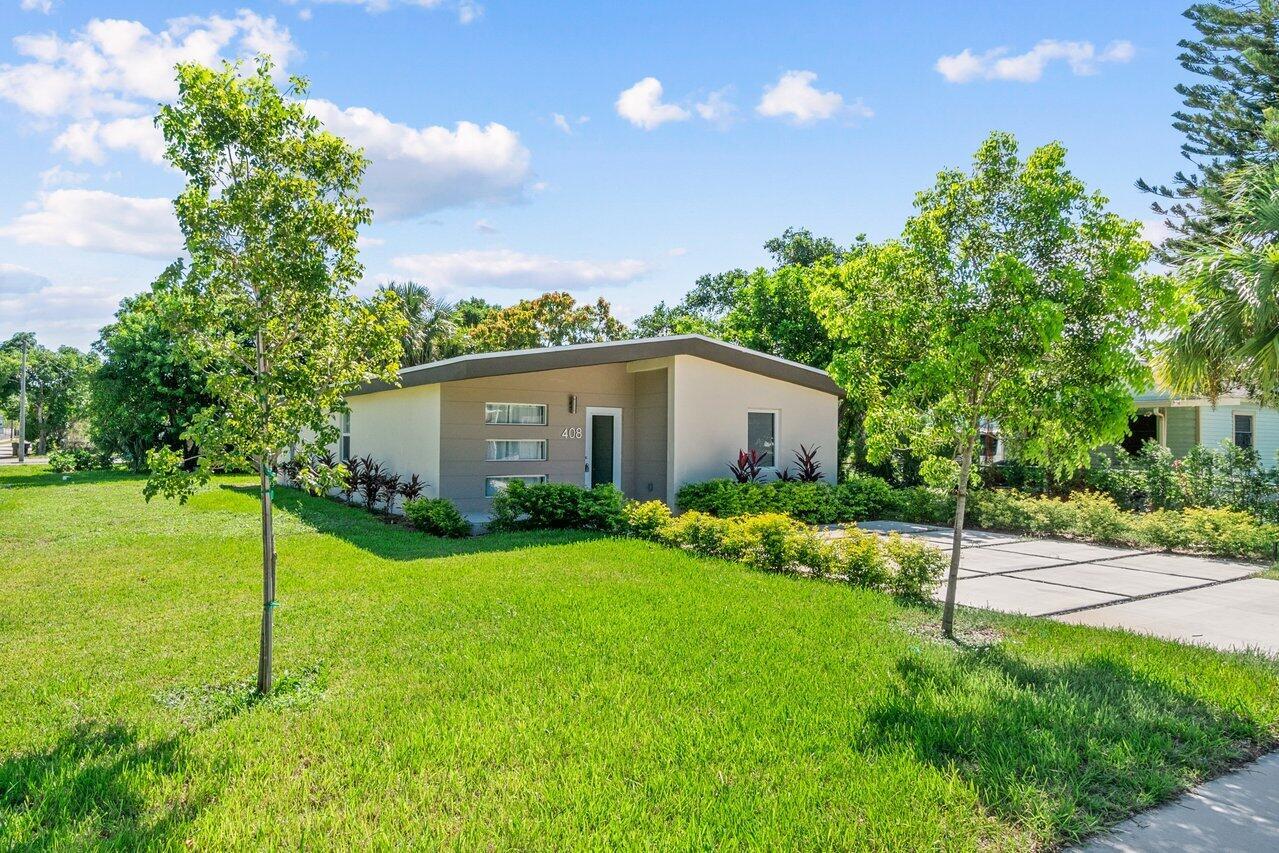A single-story house with a flat roof and a concrete driveway sits on a lawn — 408 SW 4th Street, Delray Beach FL 33444, DELRAY BEACH, FL
