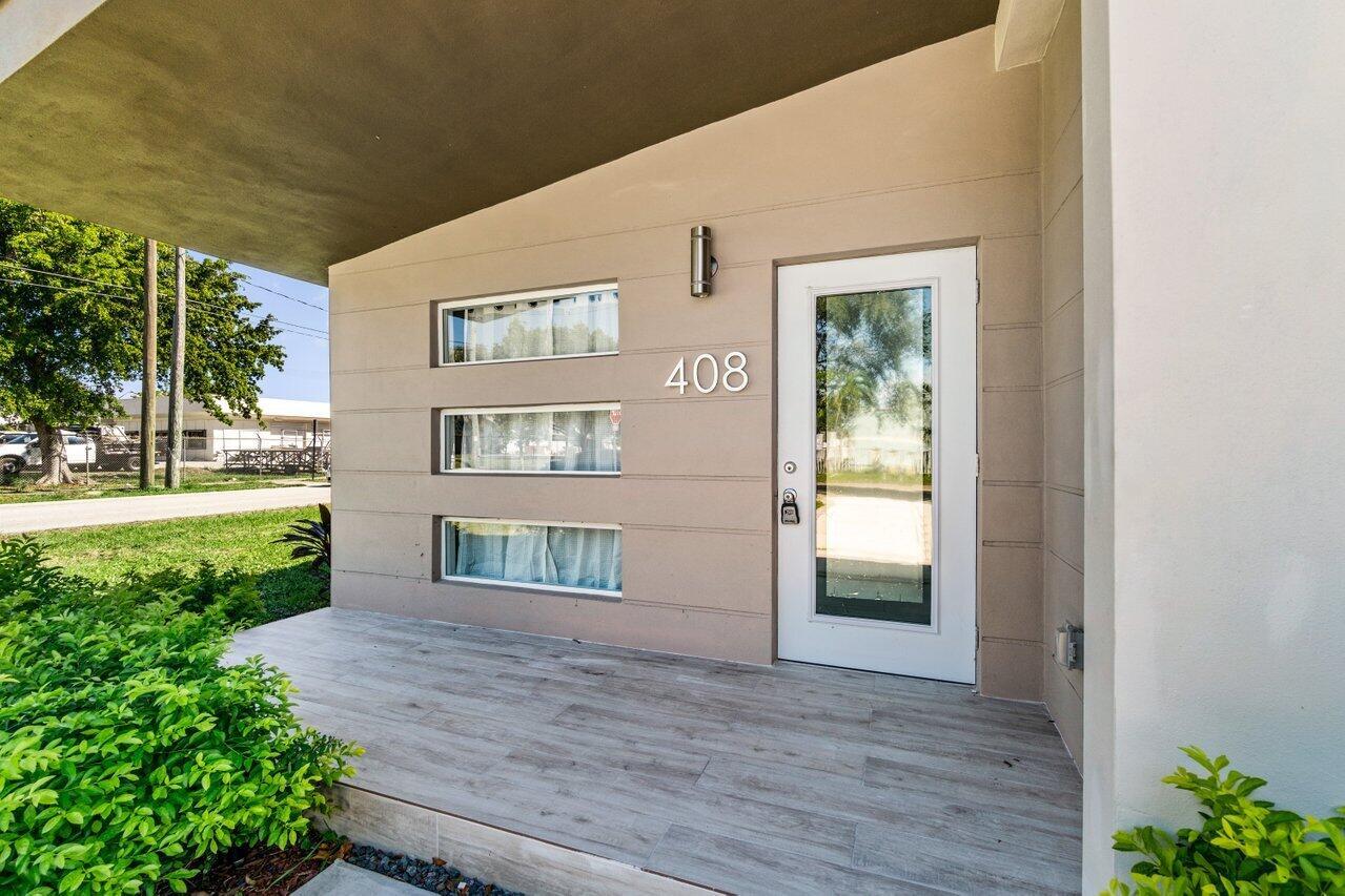 A modern exterior entryway features a white door, horizontal windows, and wood-look tile flooring — 408 SW 4th Street, Delray Beach FL 33444, DELRAY BEACH, FL
