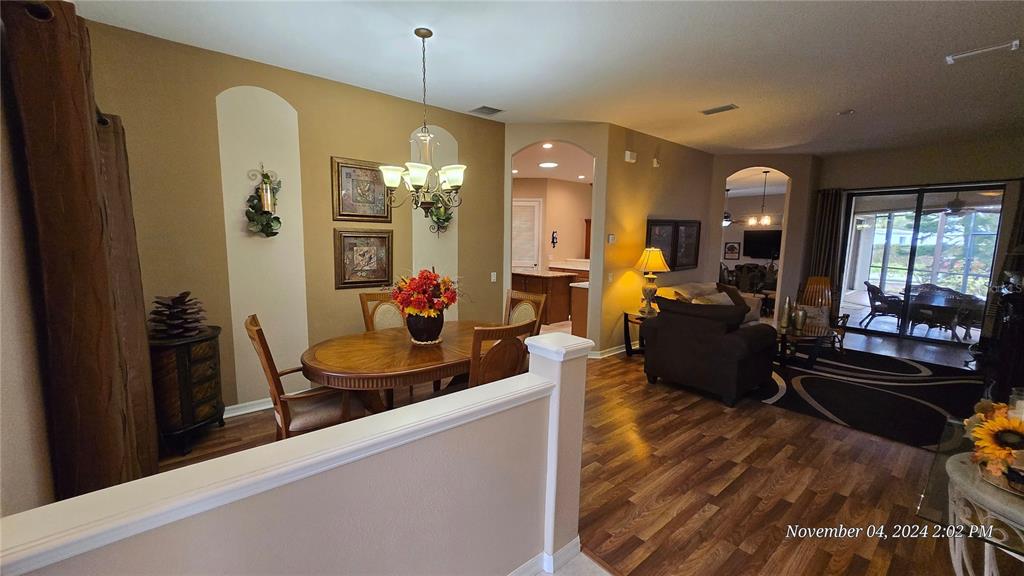 A dining area with a wooden table and chandelier opens into a living room — 24412 LAKEVIEW PLACE, PUNTA GORDA, FL