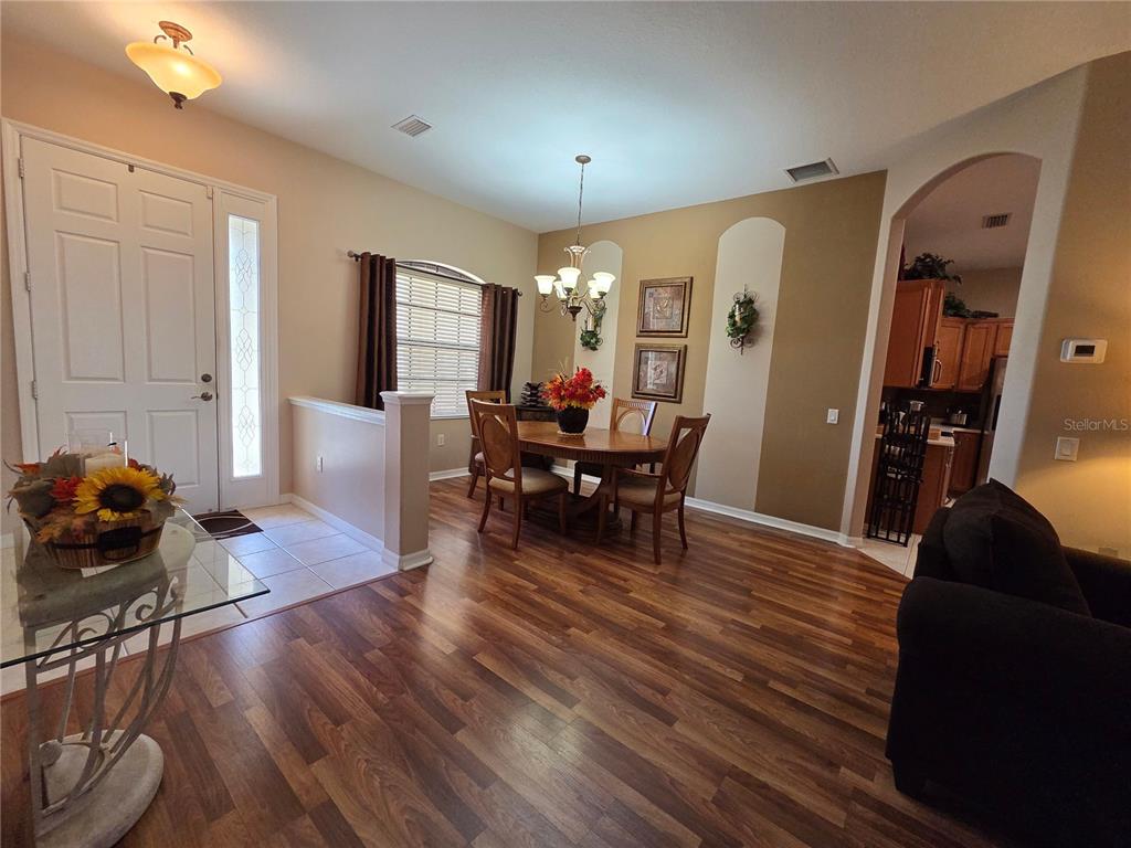 A dining area features wood flooring, a chandelier, and a partial wall near the entryway — 24412 LAKEVIEW PLACE, PUNTA GORDA, FL