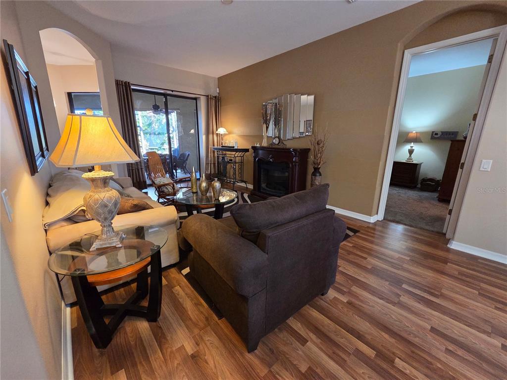 A living room features wood-look flooring, a fireplace, a glass coffee table, and a sofa — 24412 LAKEVIEW PLACE, PUNTA GORDA, FL