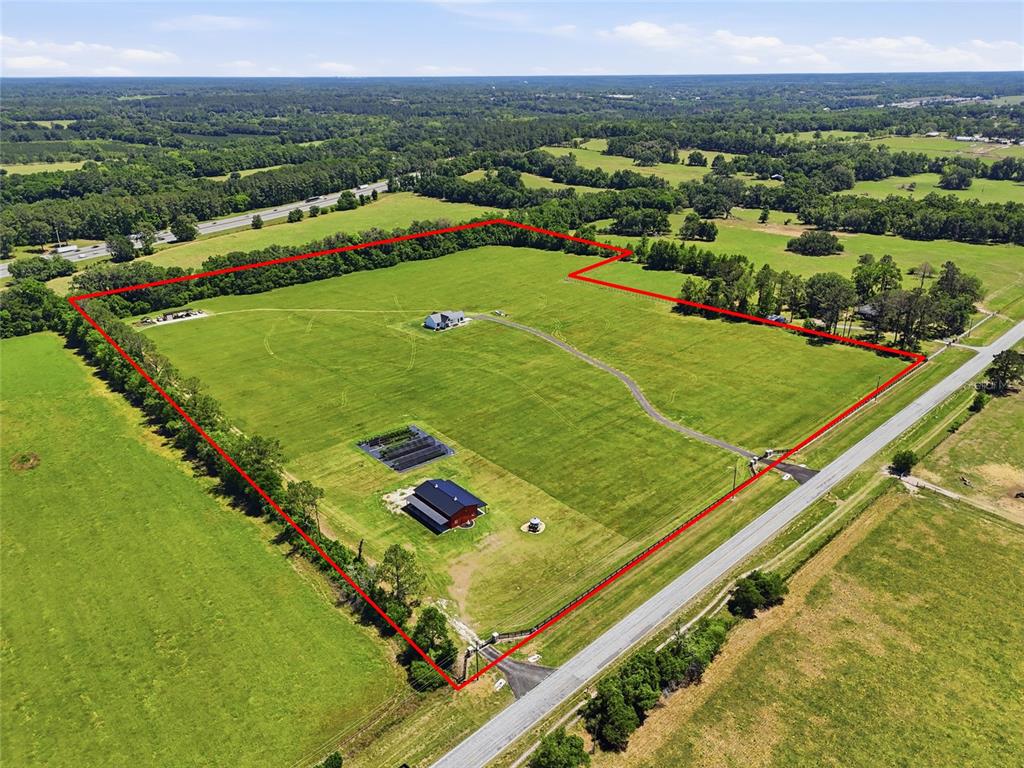 An aerial view shows a large, fenced rural property with a house, barn, and driveway — 18605 NW COUNTY ROAD 235A, ALACHUA, FL