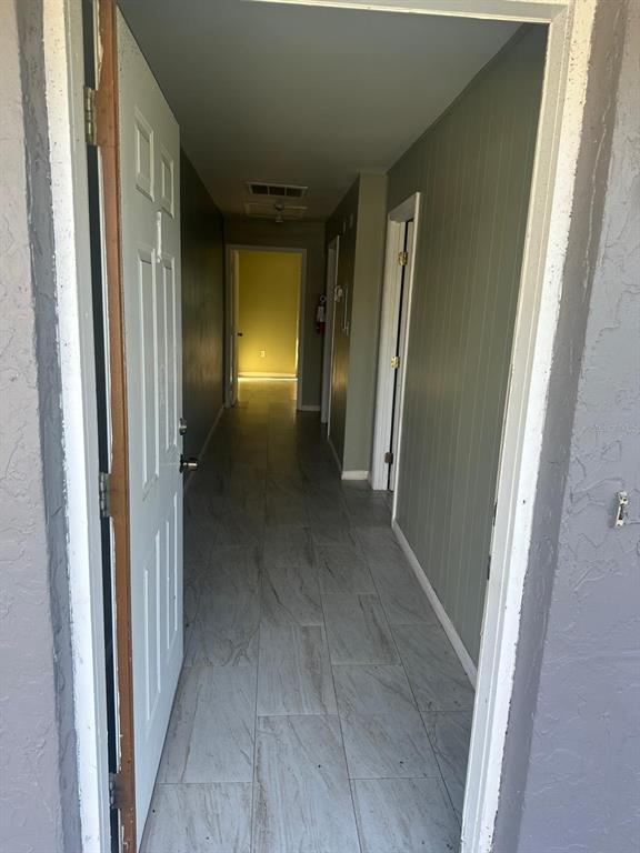 A view through an open door into a hallway with light-colored tile flooring — 214 N CHESTNUT ROAD, LAKELAND, FL