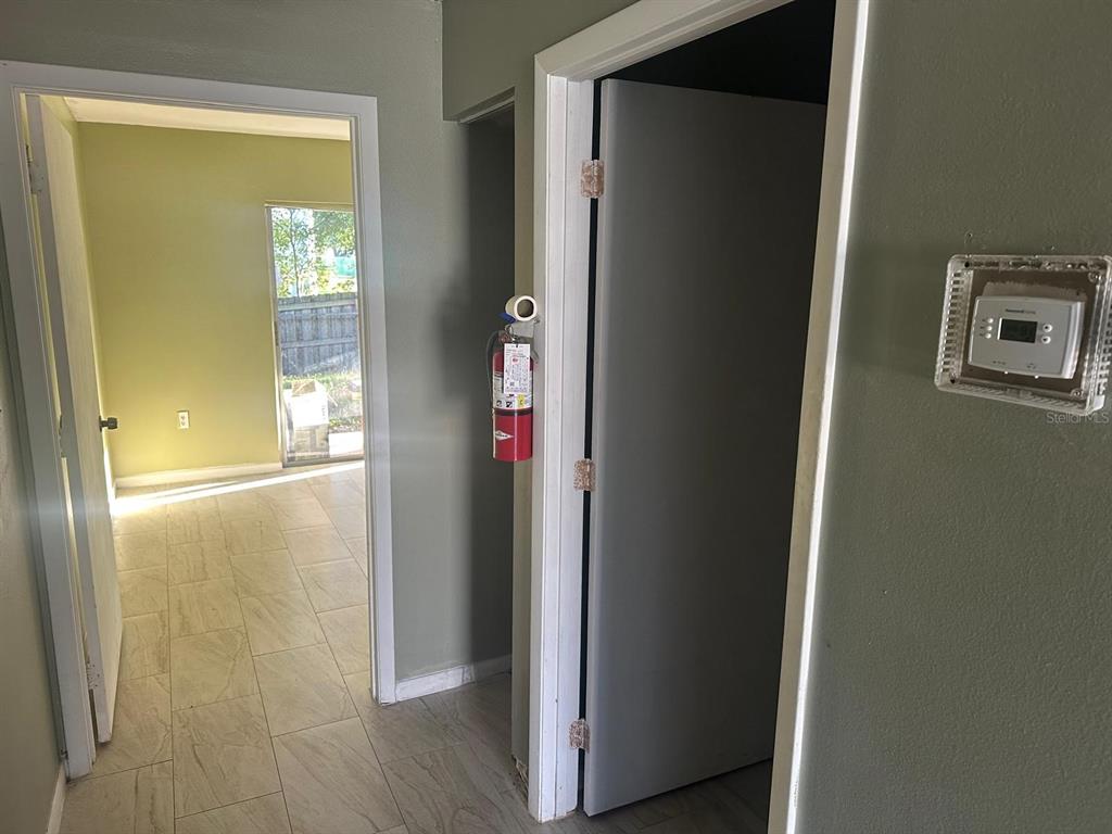 A hallway with tile flooring leads to a room with a sliding glass door — 214 N CHESTNUT ROAD, LAKELAND, FL