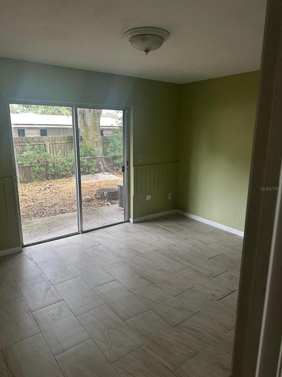 A room with light-colored tile flooring, olive green walls, and a sliding glass door — 214 N CHESTNUT ROAD, LAKELAND, FL