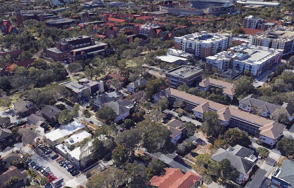 An aerial view shows a dense urban neighborhood with various buildings, trees, and parking lots — 210 NW 15TH STREET, GAINESVILLE, FL