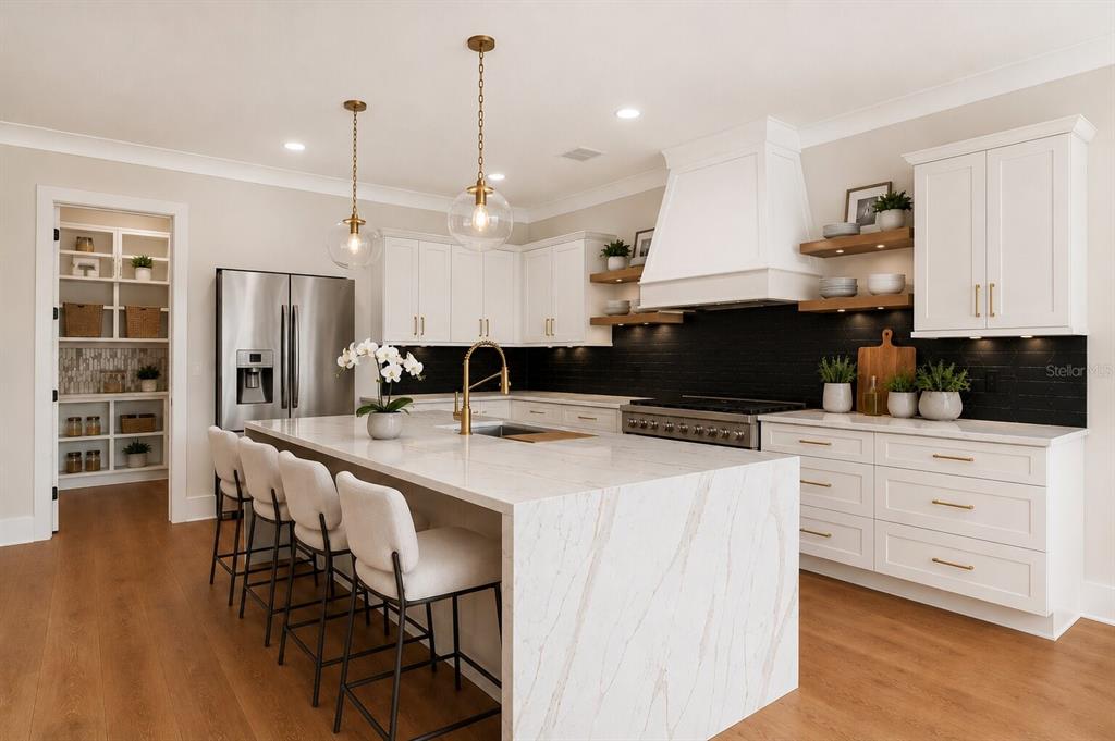 A modern kitchen features a marble waterfall island, white cabinetry, and a black tile backsplash — 4314 W VASCONIA STREET, TAMPA, FL