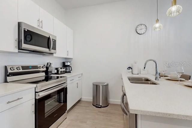 A modern kitchen features white cabinetry, stainless steel appliances, and a quartz-topped island with sink — 213 FAMAGUSTA DRIVE, DAVENPORT, FL