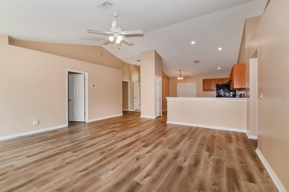 An open-concept living room with vaulted ceilings, light-colored walls, and wood-look flooring — 310 COUNTRY LAKES CIRCLE, GROVELAND, FL