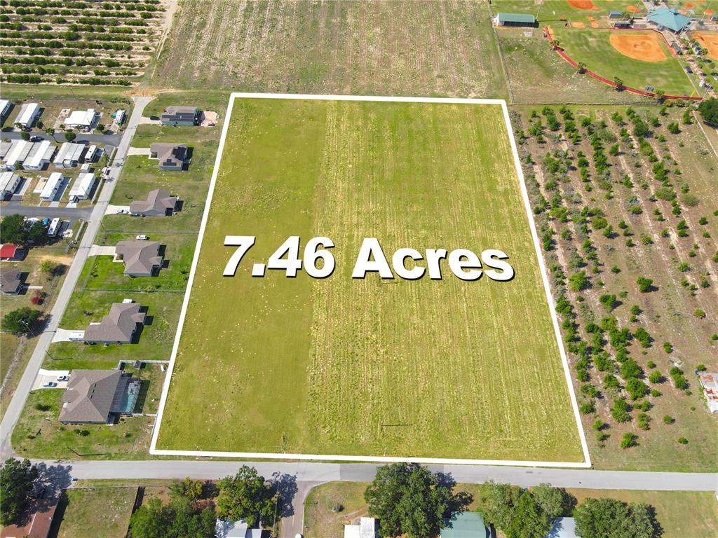 An aerial view shows a rectangular 7.46-acre plot of open land bordered by residential properties — 360 SWINGLE STREET, FROSTPROOF, FL
