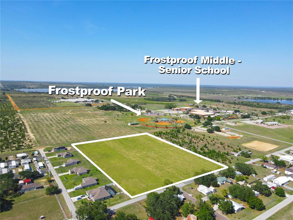 This aerial view shows a large, vacant rectangular lot near a school and park — 360 SWINGLE STREET, FROSTPROOF, FL