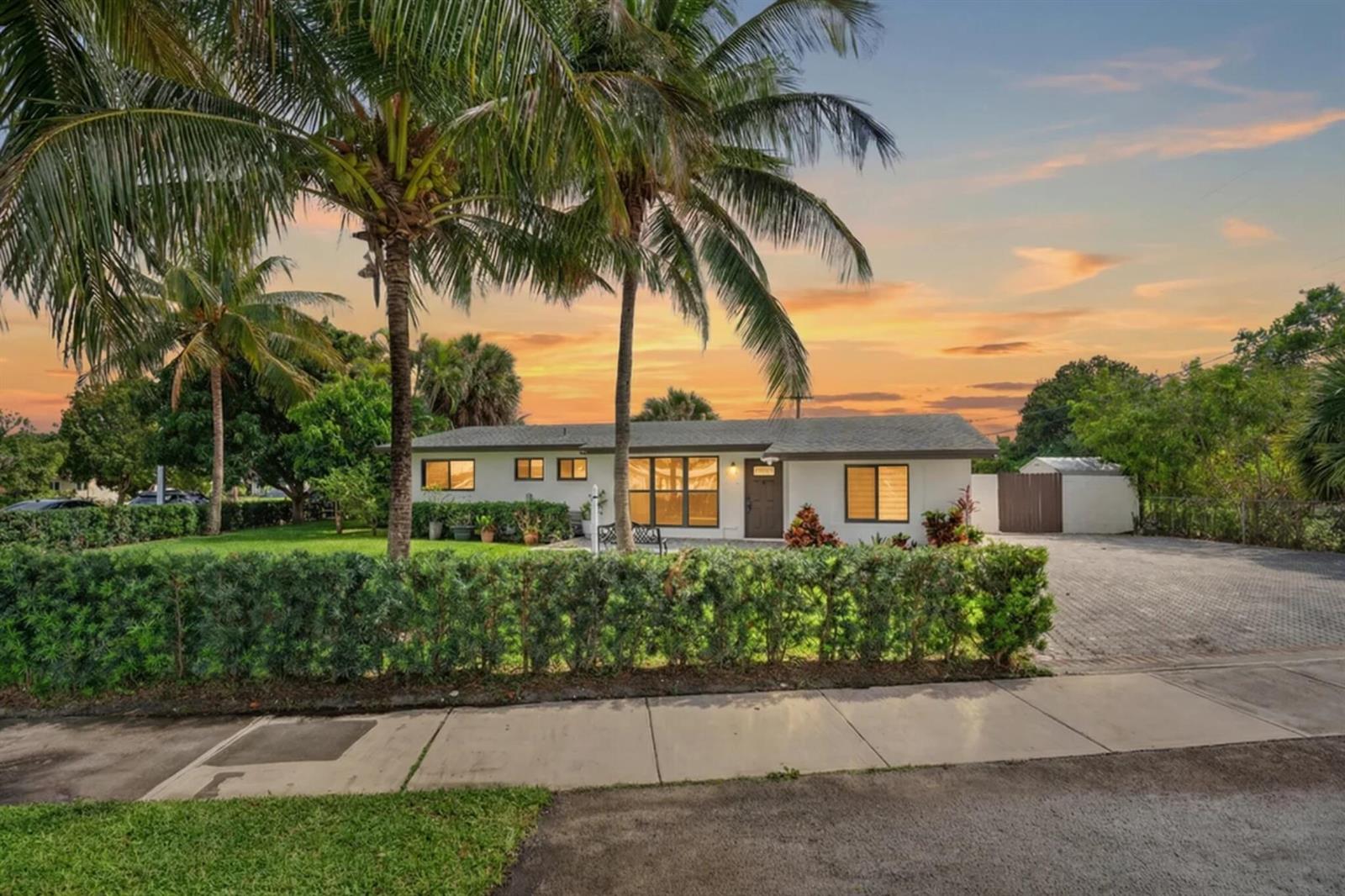 A single-story white house with a paved driveway and palm trees under a sunset sky — 5051 NE 6th Avenue, Deerfield Beach FL 33064, DEERFIELD BEACH, FL