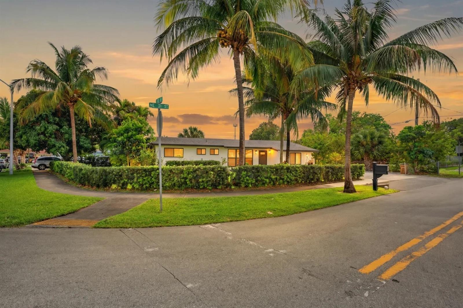 A single-story house with a hedge-lined yard and palm trees at a street corner — 5051 NE 6th Avenue, Deerfield Beach FL 33064, DEERFIELD BEACH, FL