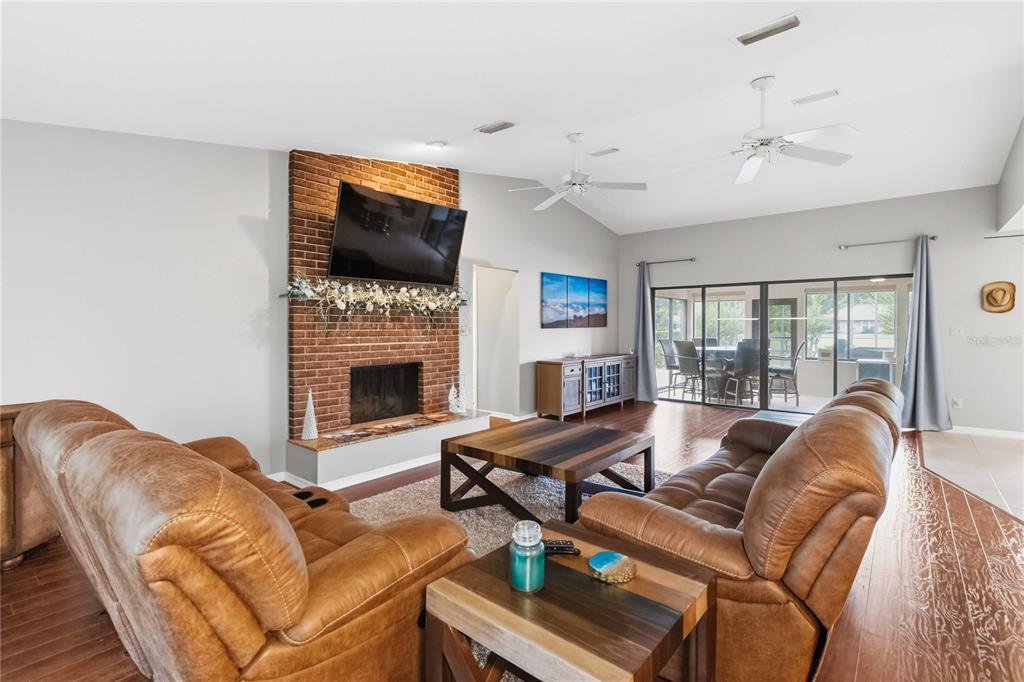 A living room features a brick fireplace, two brown leather sofas, and sliding glass doors — 5367 CROOKED OAK CIRCLE, ST CLOUD, FL