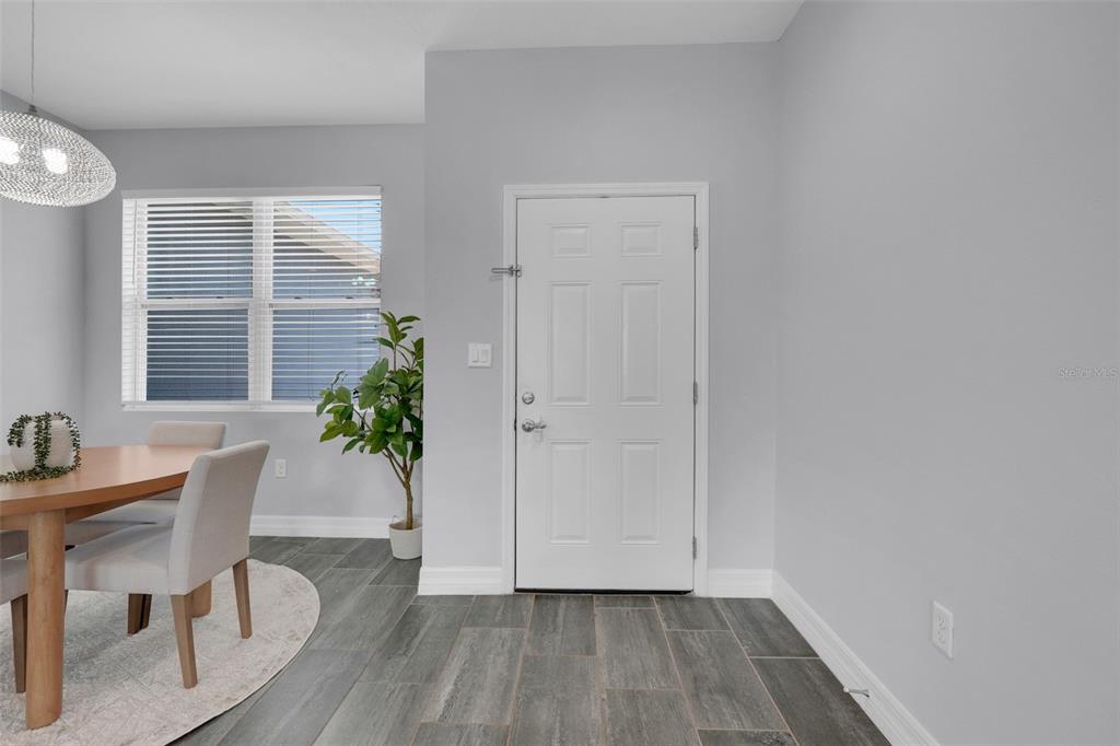 A living room features light gray walls, tile flooring, a sofa, two chairs, and sliding doors — 1109 N PLATTE LANE, POINCIANA, FL