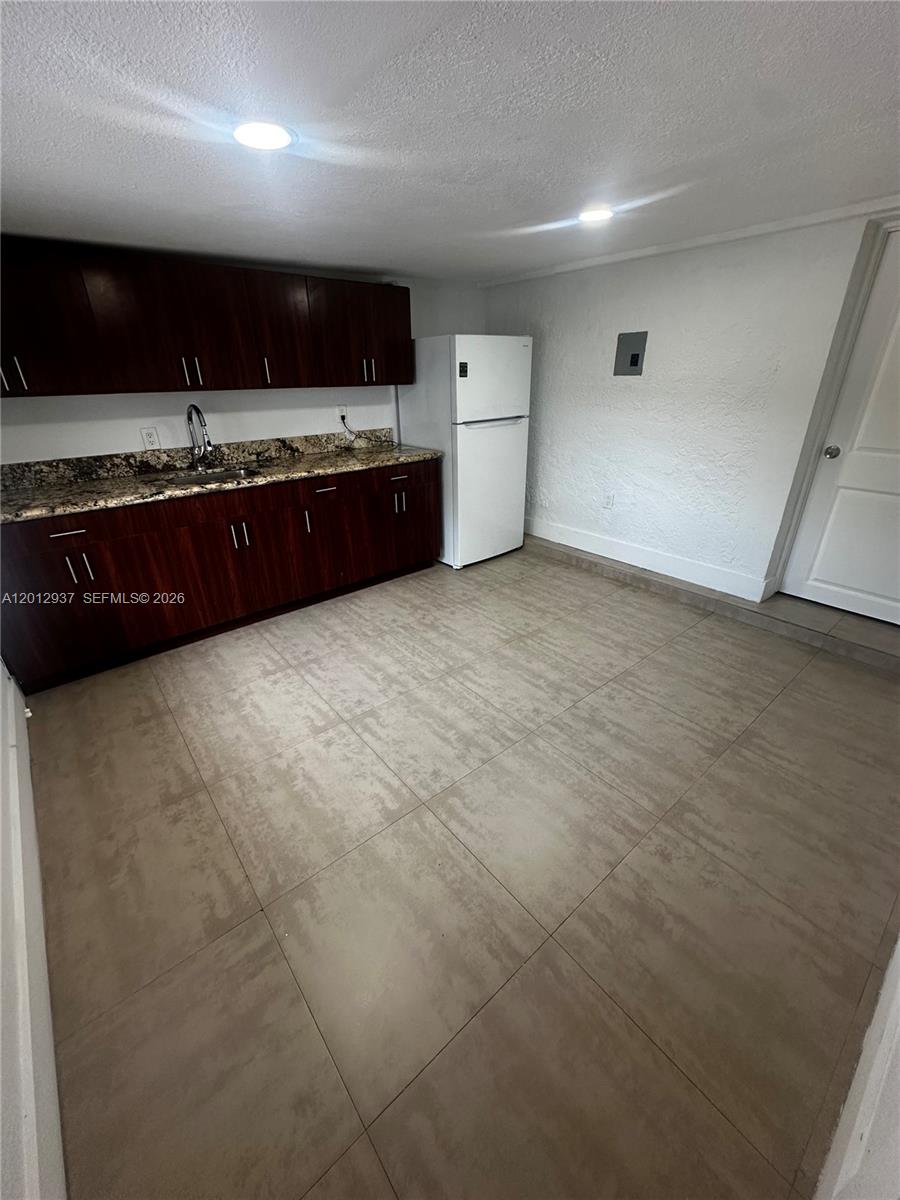 A kitchen features dark wood cabinets, granite countertops, a white refrigerator, and tiled flooring — 18560 SW 128th Ave # B, Miami FL 33177, MIAMI, FL