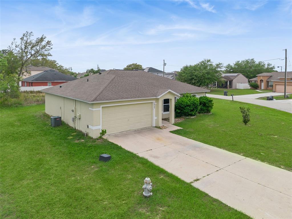 An exterior view of a single-story house with a tan stucco finish and concrete driveway — 1923 MICHIGAN COURT, KISSIMMEE, FL